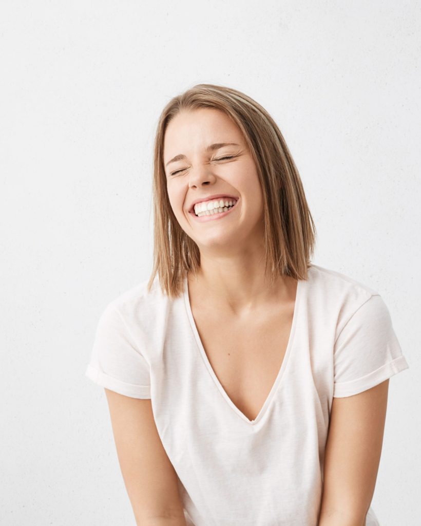 Positive human emotions. Headshot of happy emotional teenage girl with bob haircut laughing from the bottom of her heart, keeping eyes closed, showing perfect white teeth while having fun indoors
